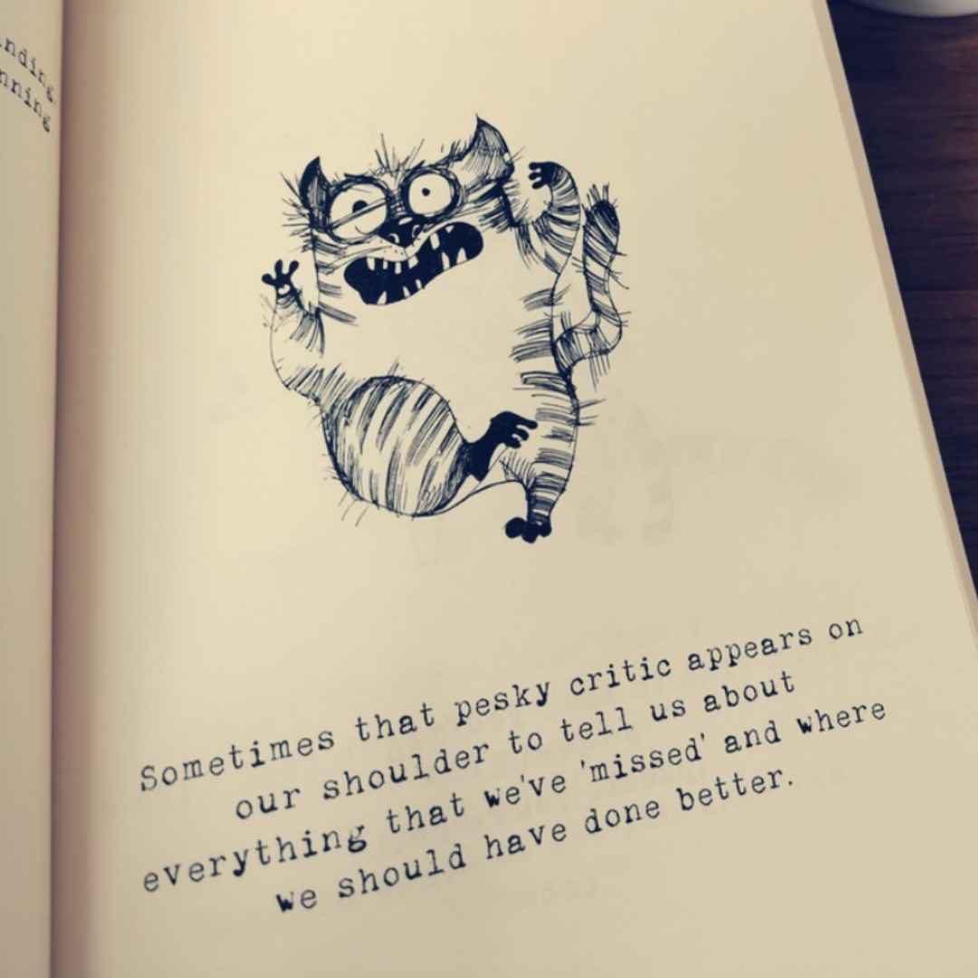 Open page of the To An Amazing gift book showing a hand-drawn panicked cat beside typewriter text about the inner critic